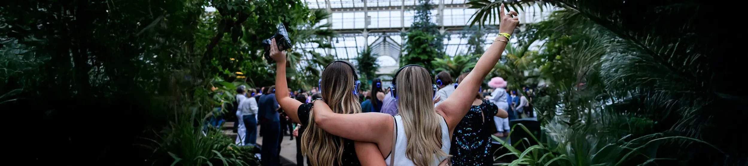 A pair of people wearing headphones at a Silent Disco in Kew Garden's Temperate House