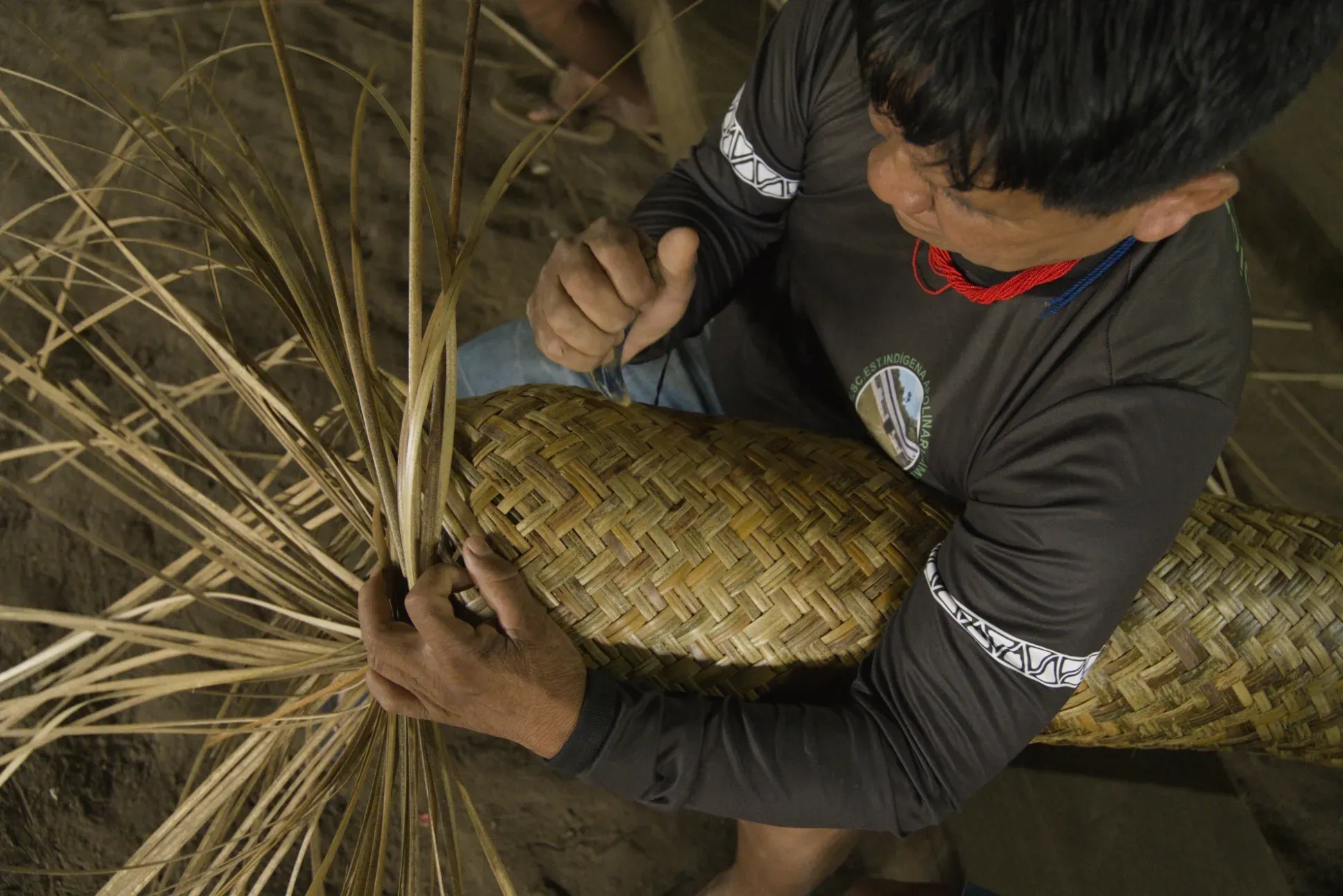 Marcos Rodrigues is weaving a tönköi (tipiti) basket from Ischnosiphon arouma, using the claw of an anteater to position the strips appropriately
