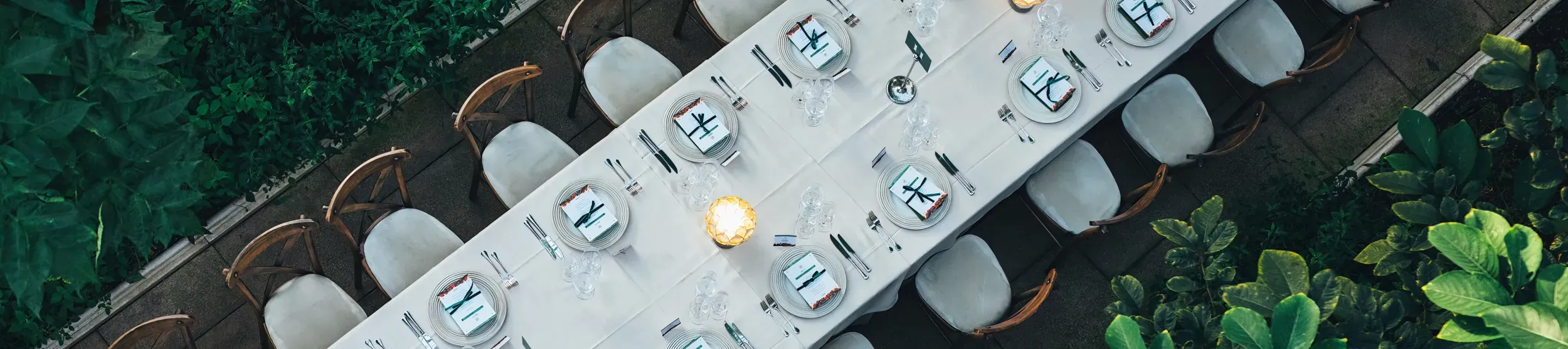 Overhead shot of banquet table in conservatory laid with table settings and a lantern