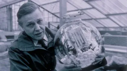 Black and white photo of David Attenborough holding time capsule that's buried in the Princess of Wales Conservatory