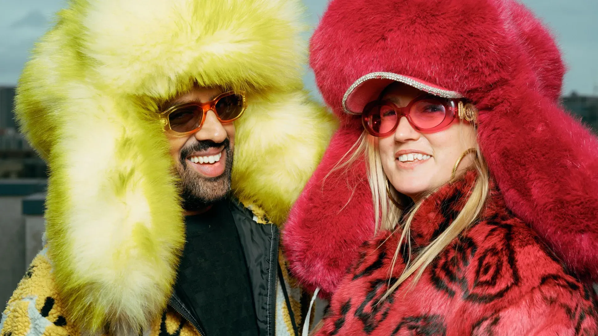 Two people wearing extra large furry hats in yellow and red