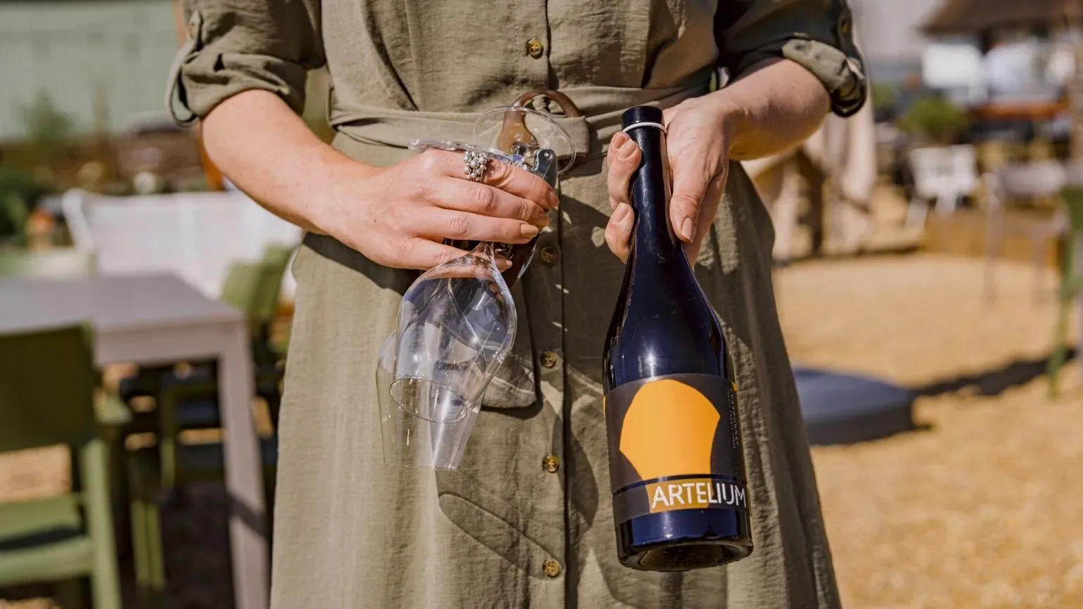 Artelium white wine bottle and wine glass being held