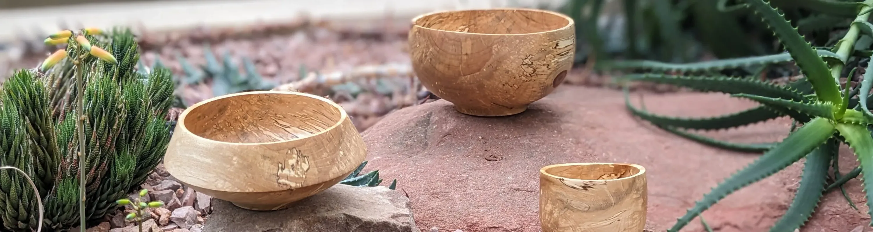 Three handmade wooden bowls arranged on gravel