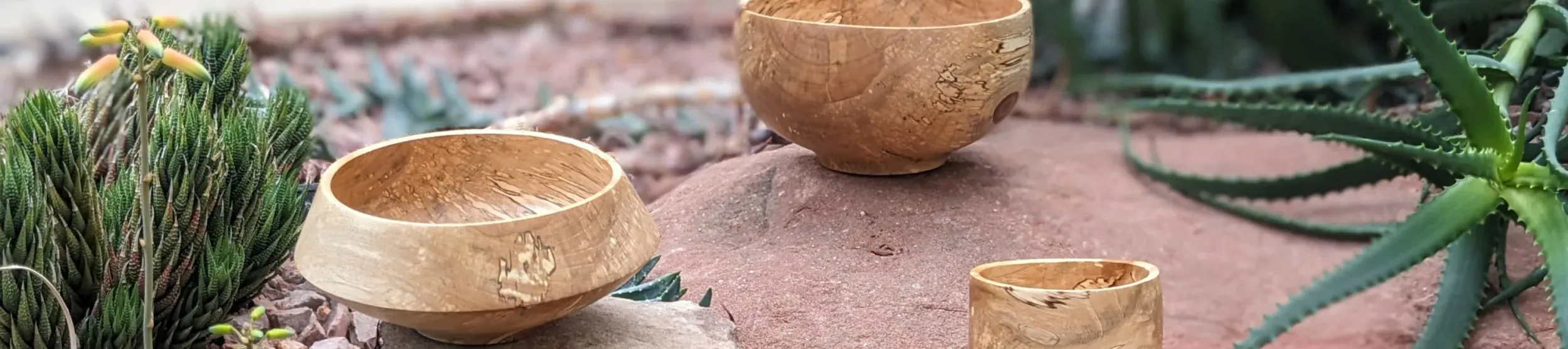 Three handmade wooden bowls arranged on gravel