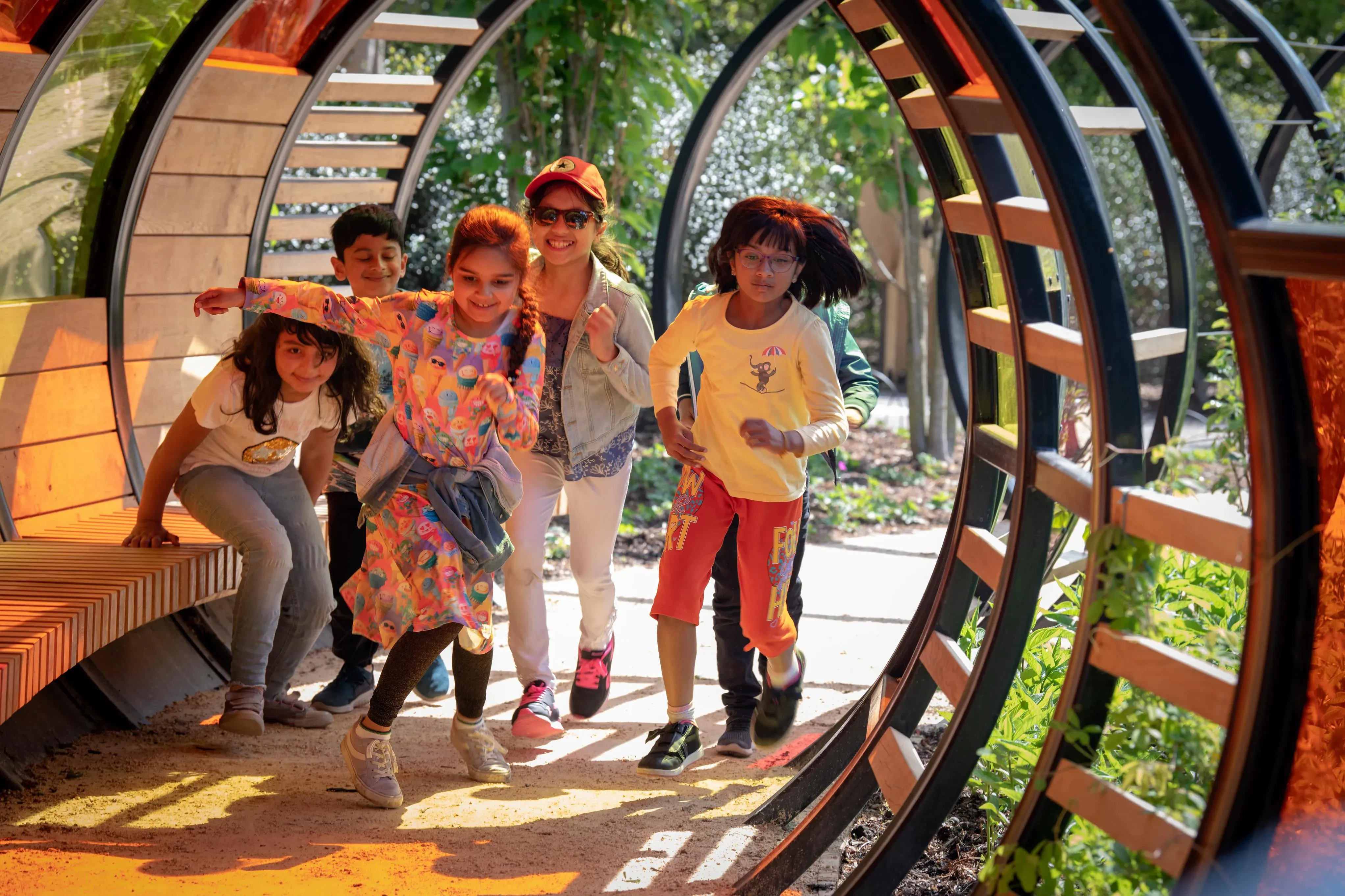 A group of children playing in a circular wooden pergola in a garden