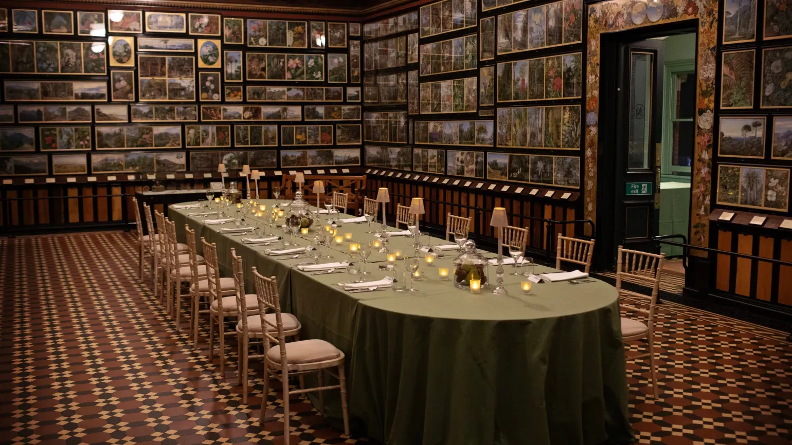 Formal tables and chairs inside a gallery lined with botanical paintings