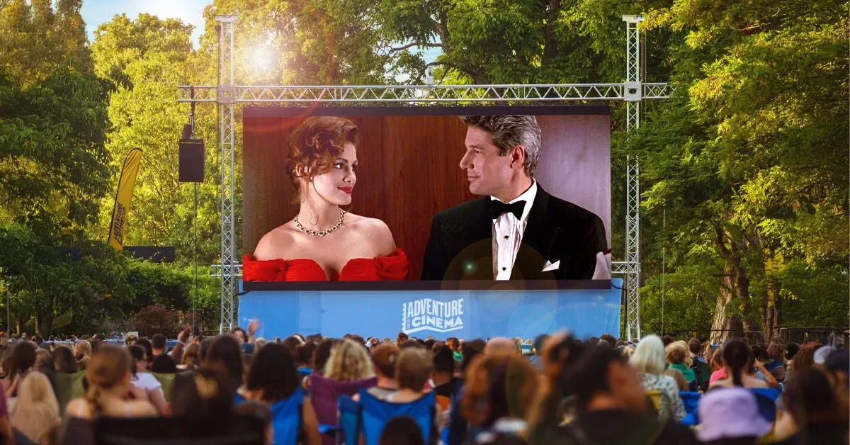 A crowd standing before an outdoor cinema screen