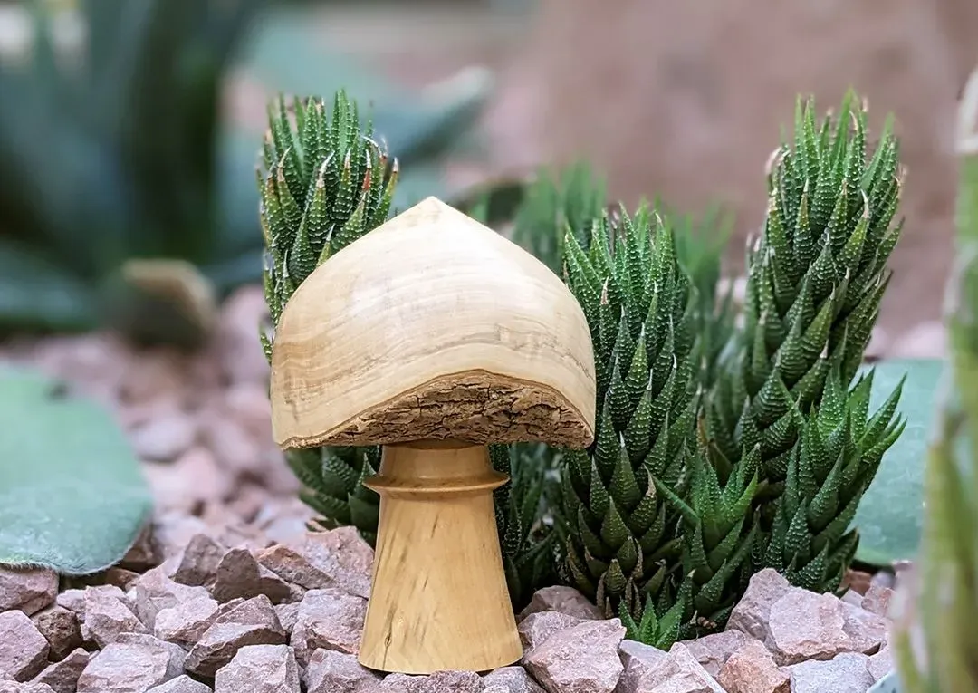 Wooden mushroom ornament placed among small stones and gravel