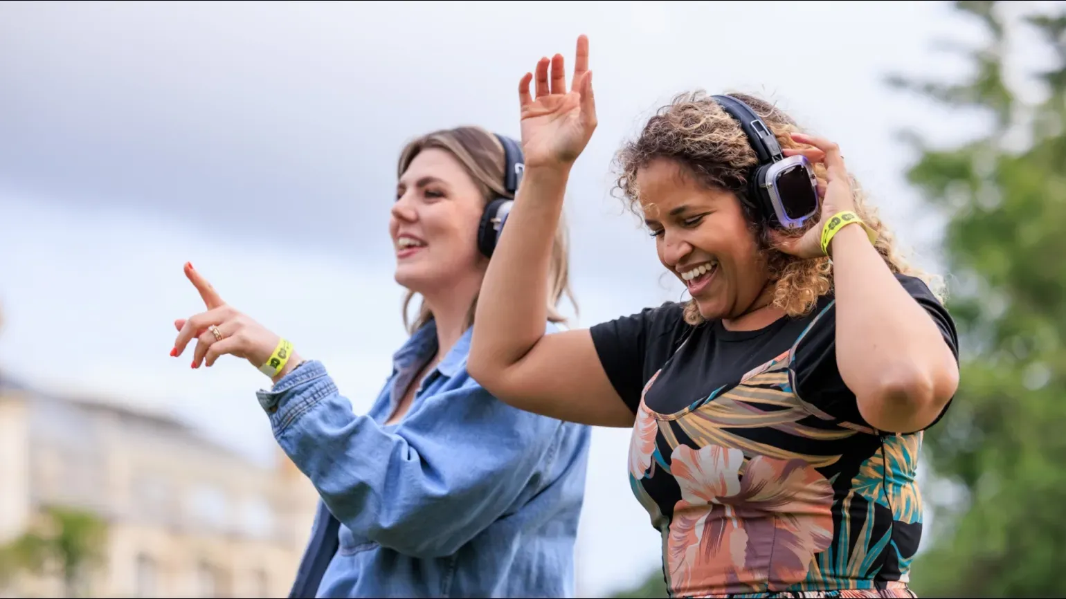 Two people dancing at a silent disco at Kew gardens with headphones on