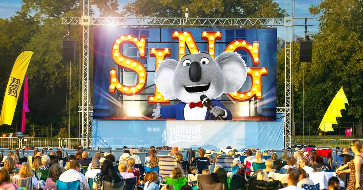 A crowd standing before an outdoor cinema screen