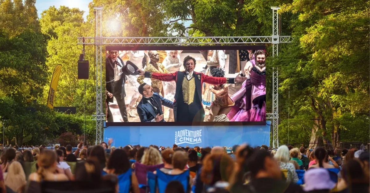 A crowd standing before an outdoor cinema screen