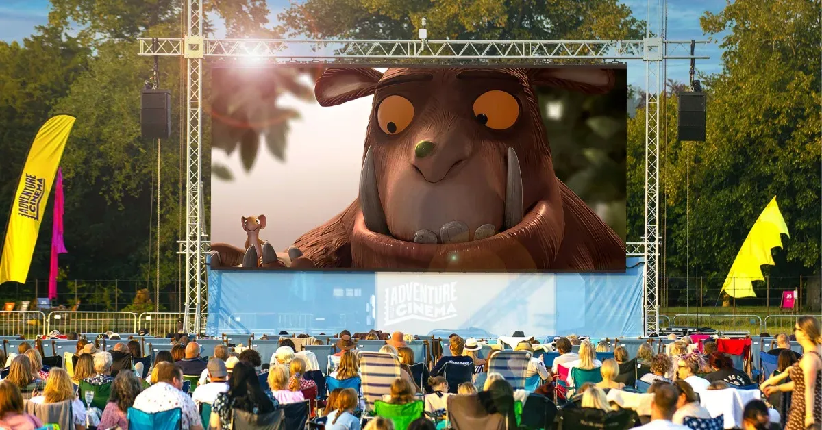 A crowd standing before an outdoor cinema screen