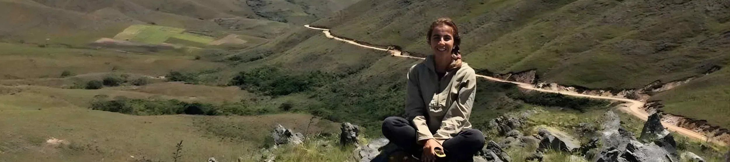 Person sits on rock in front of landscape