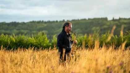 Saxophonist playing in a field in the early evening light
